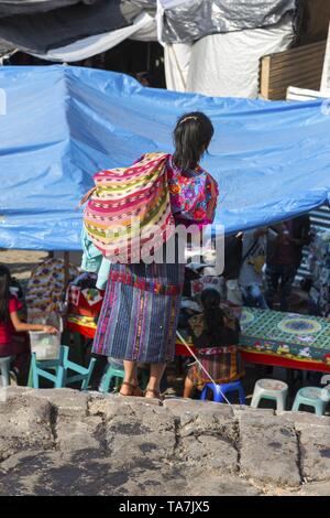 Etnica donna guatemalteco con borsa a tracolla che trasportano merci in vendita a piedi il giovedì giorno di mercato nella città di Chichicastenango, Guatemala Foto Stock