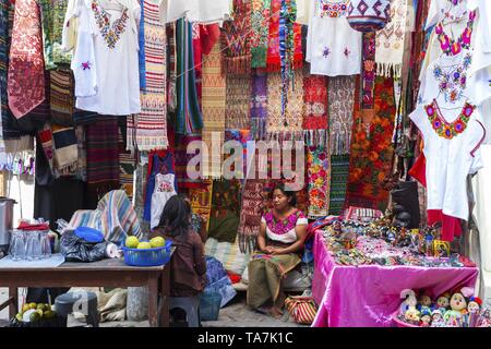 Persone di etnia seduta e la vendita di prodotti tessili tradizionali, i tappeti e i capi di abbigliamento di giovedì il giorno di mercato nella città di Chichicastenango o Chichi Guatemala Foto Stock