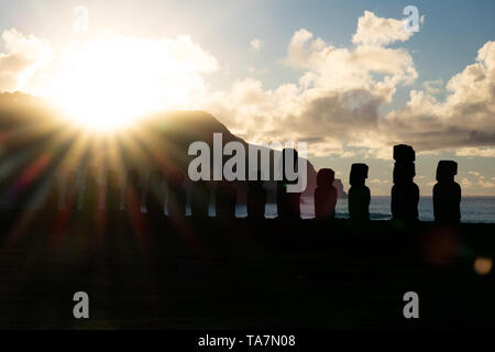 Bright sole che sorge dietro il moai sagome in Isola di Pasqua Foto Stock