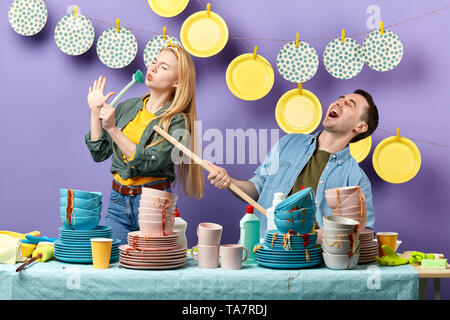 Due giovani godendo di cantare in cucina mentre il lavaggio di piatti sporchi. close up foto Foto Stock