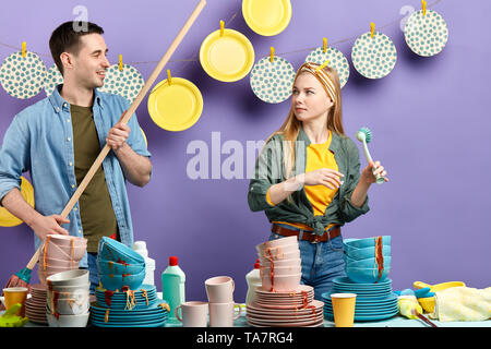 Grave donna guardando uomo sorridente mentre si lavora in cucina, guy cercando di flirtare con infelice fanciulla Foto Stock