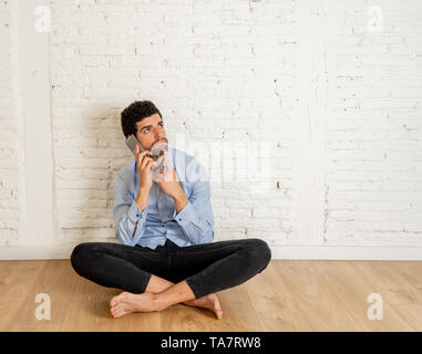 Allegro giovane hipster nuovo proprietario parlando su smart telefono cellulare nel suo nuovo piatto vuoto felice con la sua casa investimento pronto a spostare la condivisione di notizie con f Foto Stock