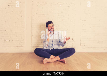 Allegro giovane hipster nuovo proprietario parlando su smart telefono cellulare nel suo nuovo piatto vuoto felice con la sua casa investimento pronto a spostare la condivisione di notizie con f Foto Stock