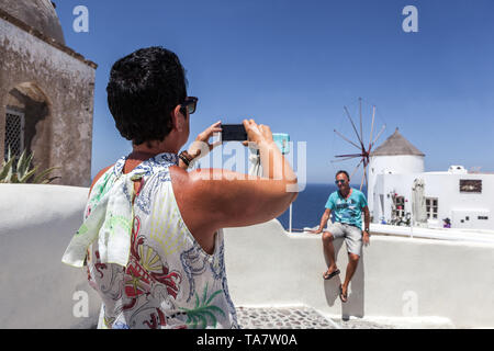 Donna che scatta una foto con vista sui mulini a vento turisti Oia Santorini Grecia Grecia vacanza Europa anziani viaggiare Foto Stock