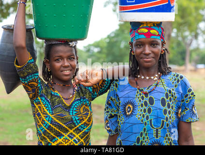 Ritratto di etnia Peul ragazze trasportare secchi pieni di acqua sulla testa, Savanes distretto, Boundiali, Costa d'Avorio Foto Stock