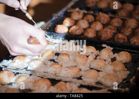 Mani di chef di cucina sfera Takoyaki canederli o polpo palle. Takoyaki sfere sono realizzati con il polpo, farina di grano tenero-basato della pastella e pan. Osaka, Giappone Foto Stock