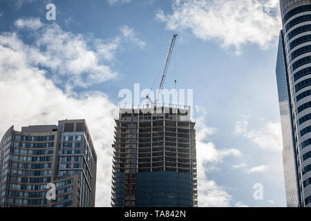 La gru e la costruzione di dispositivi su un sito di costruzione di un grattacielo nel centro cittadino di Toronto, circondato da altre alte torri e condomini nonché vecchio Foto Stock