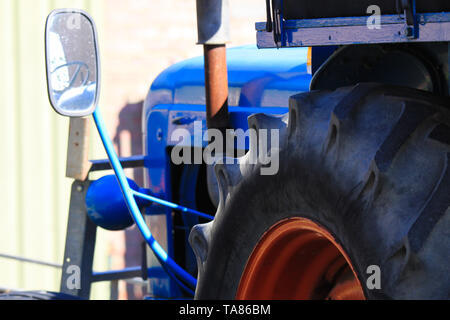 In prossimità di grandi pneumatico del vecchio blu antica antico trattore con lo specchietto retrovisore e il motore in una fattoria in Paesi Bassi Foto Stock