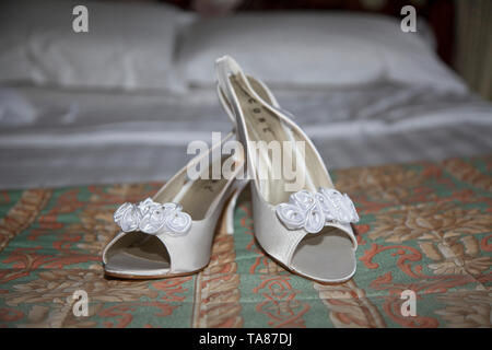 Brides wedding scarpe poste nella sua camera da letto prima che lei si sposa il giorno delle nozze, scarpe nuziale sul display durante la sposa prep Foto Stock