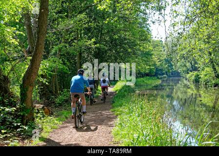 Ciclisti sul canale di navigazione River Wey in una giornata estiva, Byfleet Surrey Inghilterra UK Foto Stock