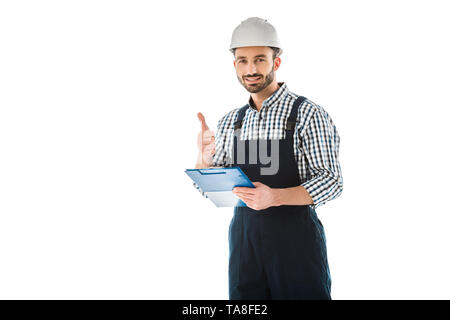 Sorridente lavoratore edile con appunti che mostra un pollice alzato e cercando nella fotocamera isolato su bianco Foto Stock