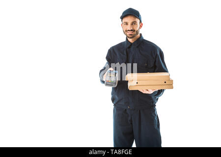 Corriere sorridente in tuta tenendo il terminale di pagamento e scatole per pizza isolato su bianco Foto Stock