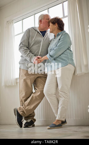 Senior uomo baciare il suo partner sulla fronte. Foto Stock