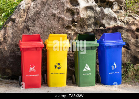Colori diversi contenitori di cestino per l'immondizia separazione con segno e icona vicino alla spiaggia per turisti Foto Stock