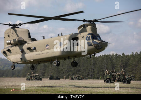 Un U.S. Esercito CH-47 elicottero Chinook, assegnato al Bravo Company, 2° Battaglione, 1a combattere la Brigata Aerea, 1a divisione di fanteria, decolla l'elicottero zona di atterraggio (HLZ) per condurre un assalto dell'aria la missione con i paracadutisti assinged per attaccare Company, 1° Battaglione, 503rd Reggimento di Fanteria, 173rd Brigata Aerea, caricati a bordo durante l'esercizio una risposta immediata a Vojarna Josip Jovic Airbase, Udbina, Croazia, 17 maggio 2019. Esercizio risposta immediata è un esercizio di multinazionale co-guidato dal croato di Forze Armate, Sloveno Forze Armate, E DEGLI STATI UNITI Esercito europeo. La logistica-focalizzata exerci Foto Stock