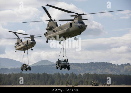 Due Stati Uniti Esercito CH-47 elicottero Chinook, assegnato al Bravo Company, 2° Battaglione, 1a combattere la Brigata Aerea, 1a divisione di fanteria, conduce un assalto dell'aria missione con imbracatura equipaggiamento caricato insieme con i paracadutisti assegnato alla società di attacco, 1° Battaglione, 503rd Reggimento di Fanteria, 173rd Brigata Aerea, caricati a bordo durante l'esercizio una risposta immediata a Vojarna Josip Jovic Airbase, Udbina, Croazia, 17 maggio 2019. Esercizio risposta immediata è un esercizio di multinazionale co-guidato dal croato di Forze Armate, Sloveno Forze Armate, E DEGLI STATI UNITI Esercito europeo. La logistica-focalizzata esercizio è design Foto Stock