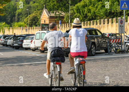GARDA LAGO DI GARDA ITALIA - Settembre 2018: due persone a cavallo delle biciclette e tenendo le mani in Garda sul Lago di Garda Foto Stock