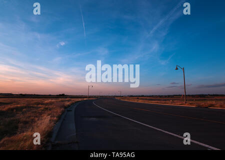 Tramonto sul vuota una strada laterale con cielo blu e un paio di nuvole Foto Stock