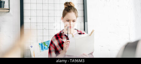 Panoramica di concentrato di adolescente tenendo pen e carte Foto Stock
