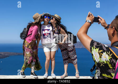 Santorini turisti tre donne in un luogo famoso in Grecia turisti scattare foto sopra il mare, isole greche turismo europeo Foto Stock