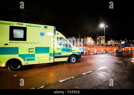 London, Regno Unito - Mar 5, 2017: Giallo NHS Ambulance guida veloce sul riparato con lavori stradali street nel centro di Londra di notte Foto Stock