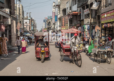 Un risciò elettrici e risciò bicicletta su una strada nel centro cittadino di Nuova Delhi, India. Foto Stock