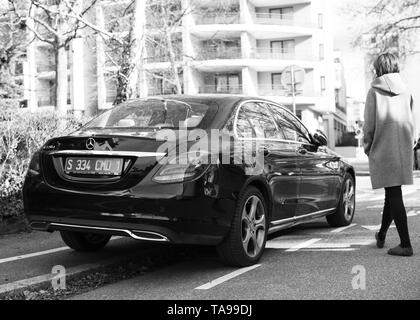 Strasburgo, Francia - Feb 23, 2017: Donna che cammina verso il nuovo status di Mercedes-Benz E220d diesel auto parcheggiata su una strada tranquilla nella città francese Foto Stock