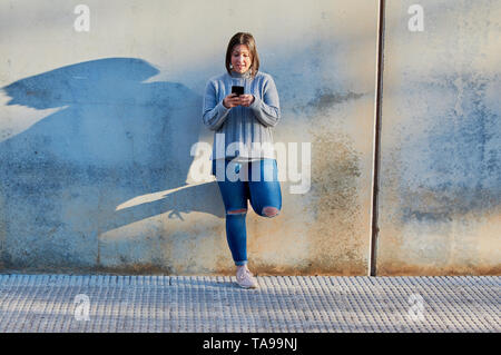 Ragazza giovane parlando su smartphone e digitare messaggi con lo smartphone Foto Stock