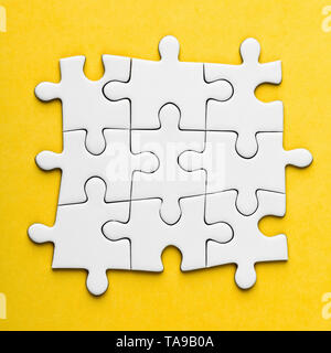 Vuoto collegato i pezzi del puzzle su sfondo giallo. Foto Stock