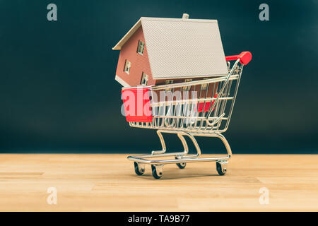 Concetto per acquisto di una casa nuova. Un modello di casa in una miniatura del carrello. Foto Stock