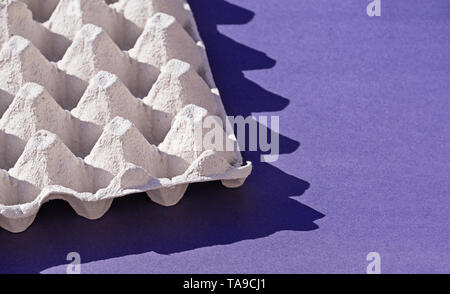 Primo piano di una scatola di carta cartone uovo per le uova sul filo viola con disco Shadows. Concetto di utilizzando imballaggio biodegradabile e di ridurre il consumo di plastica, spazio di copia Foto Stock