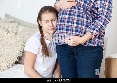 Ragazza giovane non è contento di nuovi gemelli, chiudendo gli occhi e piangendo lungo la sua gravidanza madre Foto Stock