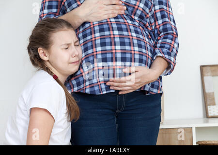 A piangere la figlia infelice appoggiata ventre della donna incinta, bambino non desidera che il fratello Foto Stock