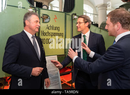 23 maggio 2019, Sassonia, Dresda: Andreas Scheuer (CSU, M), Ministro federale dei trasporti, Claus Weselsky (l), presidente del sindacato tedesco dei macchinisti e Michael Kretschmer (CDU), il Ministro Presidente del Land di Sassonia, sono in piedi presso il Museo dei Trasporti su un S & H locomotiva di prova con la scritta 'Achtung Hochspannung 10.000 Volt' dopo l'atto di fondazione per il Centro tedesco per il trasporto ferroviario di ricerca. Foto: Robert Michael/dpa-Zentralbild/dpa Foto Stock