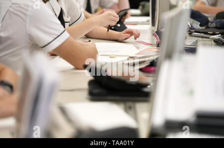 Occupato scuola di alta classe con studenti in bianco uniforme e legami lavora con libri, penne, matite, gomme, tecnologia. Gli studenti che lavorano in classe Foto Stock