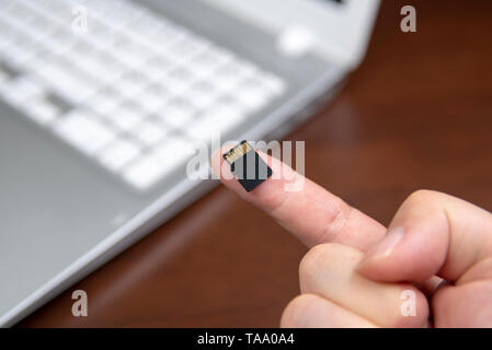 Mano umana l'inserimento di una micro scheda SD nel personal computer portatile Foto Stock