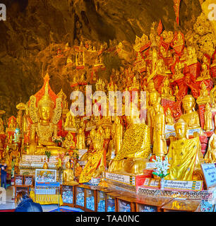 PINDAYA, MYANMAR - 19 febbraio 2018: Numerosi golden statue e sculture di Buddha su red troni o circondati da reredos, situato in Pindaya cav Foto Stock