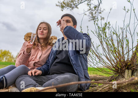 Una giovane coppia è seduta in natura acqua potabile da champagne Foto Stock