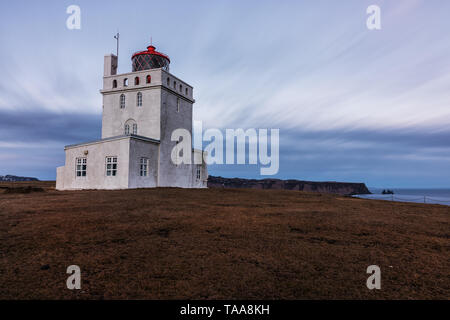 Faro Dyrholaey presa al tramonto con una lunga esposizione con nuvole a Dyrholaey, South Coast, Islanda Foto Stock