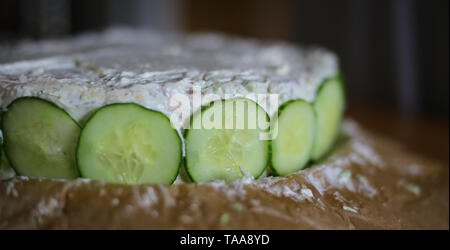 Preparazione di Smorgastarta, un tipico piatto svedese, con le fette di cetriolo. Foto Stock