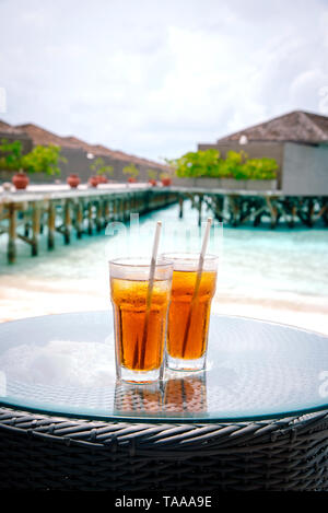 Tè freddo contro tropical Overwater Bungalow Resort sulla spiaggia, Maldive. Foto Stock