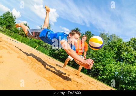 Gioco intensivo sul campo da pallavolo di spiaggia, lo spirito di lotta per salvare la sfera Foto Stock