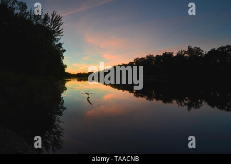 Tramonto sulla St. Croix fiume tra Minnesota e Wisconsin - alberi buia riflessa sulle acque calme - blu, arancione, rosa di colori tra le nuvole Foto Stock