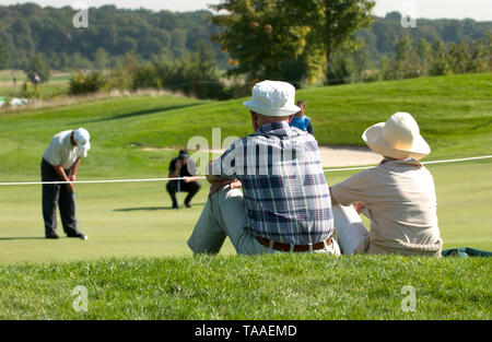 Gut LŠrchenhof in Pulheim vicino a Colonia, Germania 19.9.2003, Golf: tedesco Linde Masters --- Coppia di anziani vestiti in luce i vestiti estivi in seduta l'erba orologi professional golfers sul putting green Foto Stock