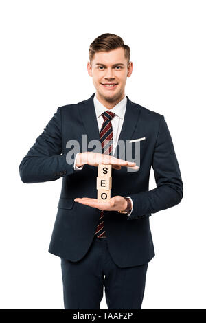 Happy businessman holding cubi di legno con seo lettering isolato su bianco Foto Stock