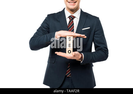 Vista ritagliata della happy businessman holding cubi di legno con seo lettering isolato su bianco Foto Stock