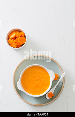 Baby carota purea in recipiente isolato su sfondo chiaro Foto Stock