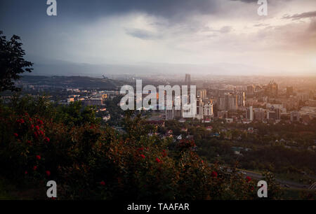 Almaty city view da Kok-tobe Mountain al drammatico tramonto tempestoso sullo sfondo del cielo Foto Stock