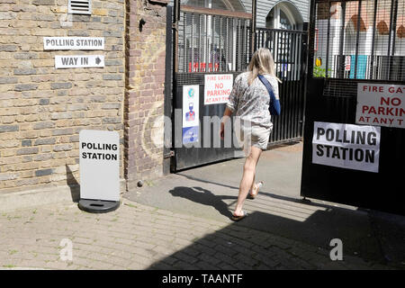 Una donna che cammina in una stazione di polling di votare alle elezioni europee, Portobello Road, Royal Borough di Chelsea e Kensington Foto Stock