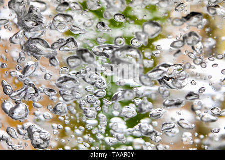 Il punto di ebollizione e acqua frizzante in un vaso di vetro, bolle e schizzi - abstract background. Foto Stock